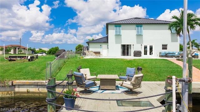 back of house featuring a patio, a lawn, french doors, and a water view