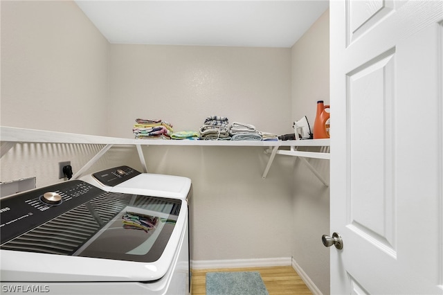 clothes washing area with light hardwood / wood-style flooring and washer and dryer