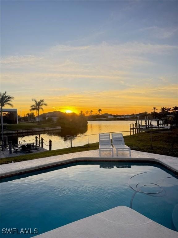 pool at dusk with a water view and a boat dock