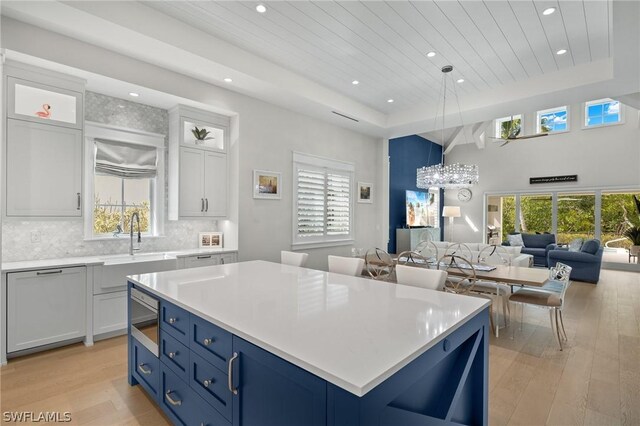 kitchen featuring wood ceiling, a kitchen island, light hardwood / wood-style flooring, white cabinetry, and hanging light fixtures