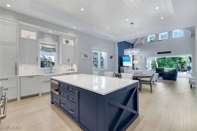 kitchen with light wood finished floors, a raised ceiling, dishwasher, and light countertops