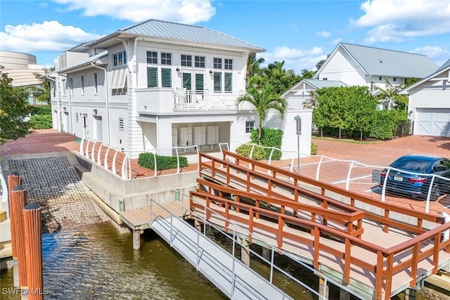 back of property featuring metal roof, a water view, and a balcony