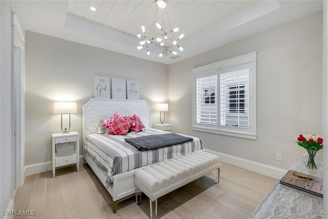 bedroom with a raised ceiling, baseboards, and wood finished floors