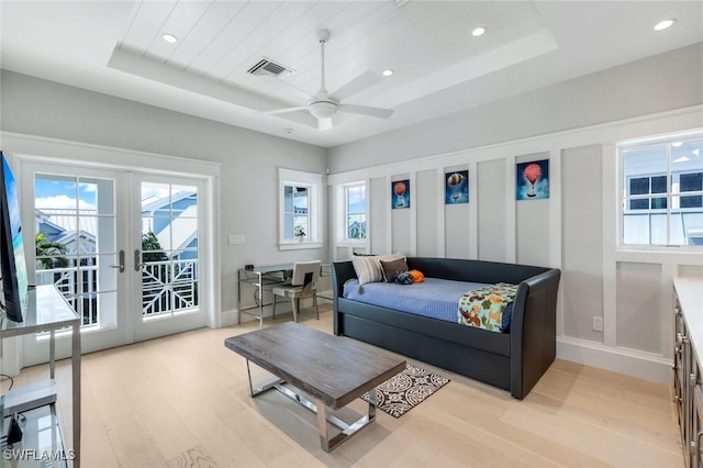 bedroom featuring visible vents, light wood-style floors, access to exterior, french doors, and a raised ceiling