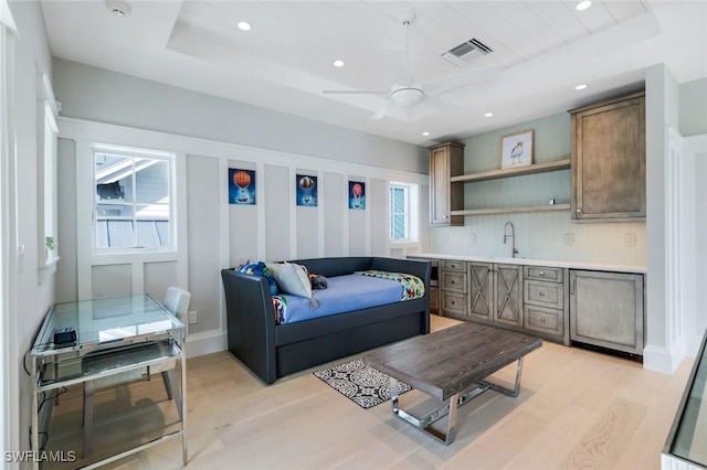 living room featuring light wood finished floors, visible vents, a raised ceiling, and recessed lighting