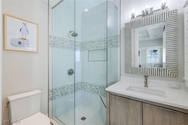 bathroom with toilet, a shower stall, and vanity