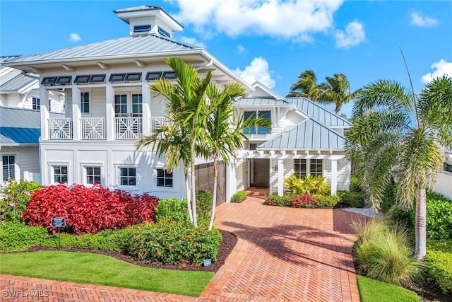 view of front of house with decorative driveway, a standing seam roof, metal roof, and a balcony