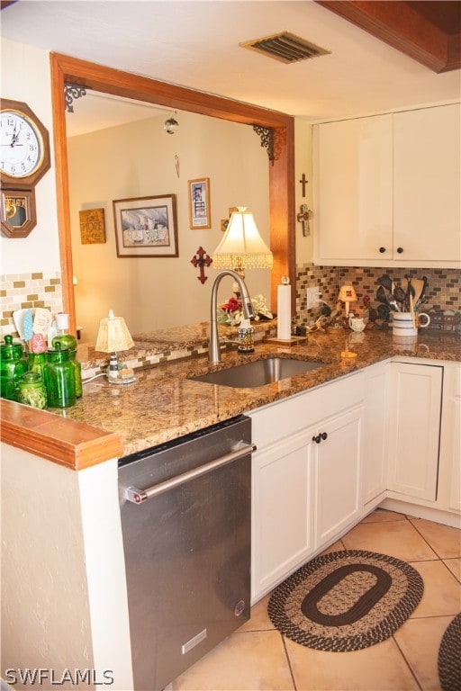 kitchen with sink, stainless steel dishwasher, decorative backsplash, dark stone countertops, and white cabinetry