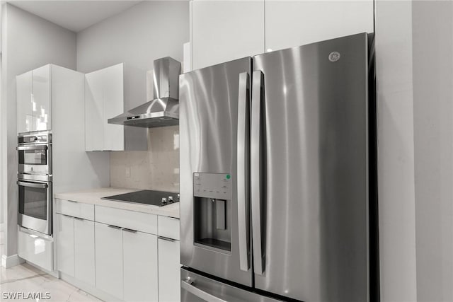 kitchen featuring tasteful backsplash, white cabinets, appliances with stainless steel finishes, and wall chimney exhaust hood