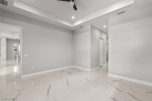 empty room featuring ceiling fan and a tray ceiling