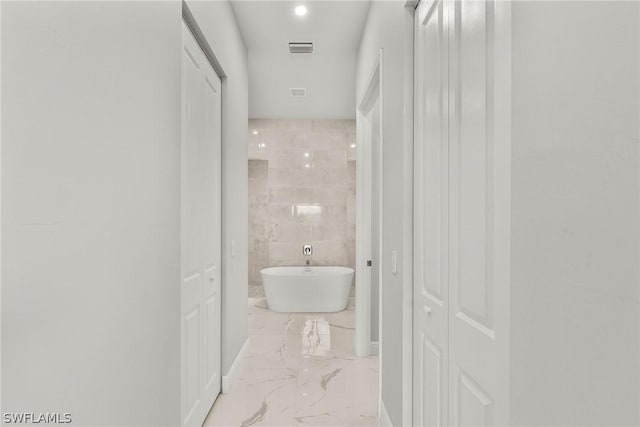 bathroom with a bathing tub and tile walls