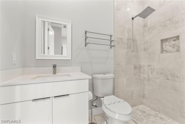 bathroom featuring tiled shower, vanity, and toilet