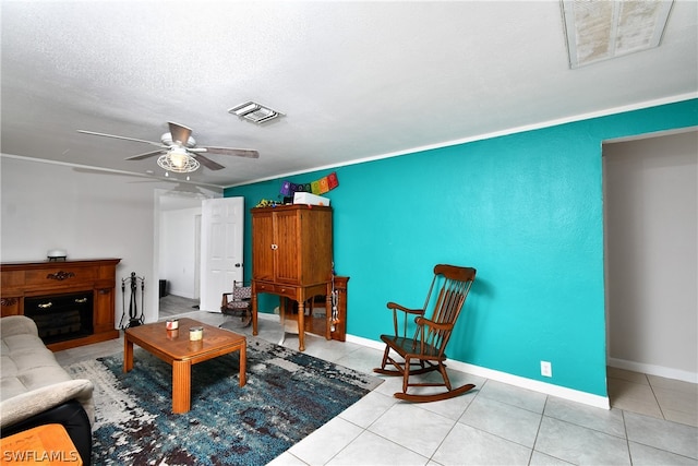 living room with a textured ceiling, light tile patterned floors, and ceiling fan