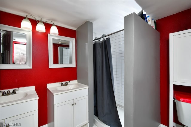 bathroom with toilet and dual bowl vanity