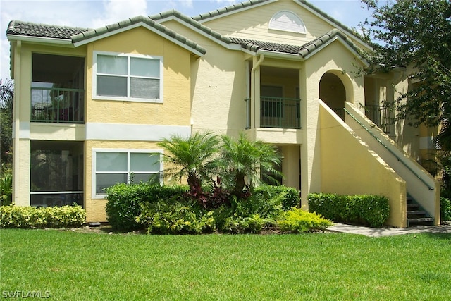 view of front of house featuring a balcony and a front yard