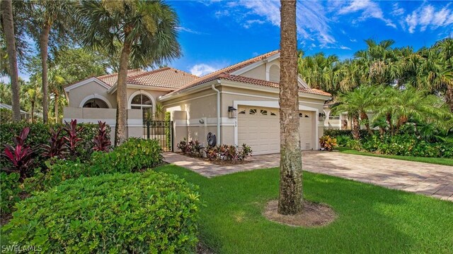 mediterranean / spanish-style house featuring a garage and a front lawn