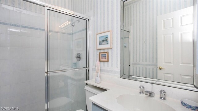 bathroom featuring vanity, toilet, and a shower with shower door