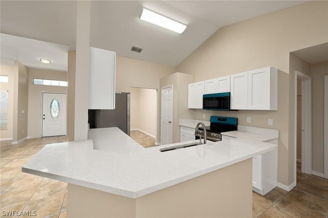 kitchen featuring kitchen peninsula, stainless steel appliances, vaulted ceiling, sink, and white cabinets