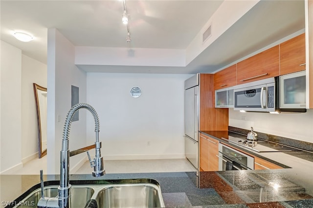 3000 Oasis Grand Blvd Unit 1704, Fort Myers, FL 33916 - kitchen with stainless steel appliances, brown cabinets, modern cabinets, dark stone counters, and rail lighting