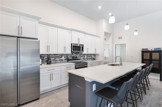 kitchen featuring stainless steel appliances, a kitchen island with sink, white cabinetry, and sink