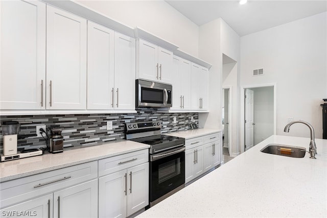 kitchen featuring light stone counters, sink, white cabinetry, and appliances with stainless steel finishes