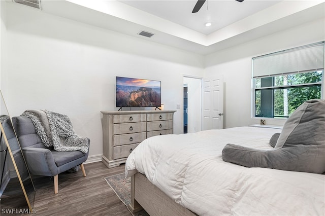 bedroom with ceiling fan, dark hardwood / wood-style floors, and a tray ceiling