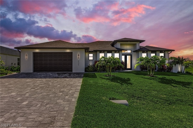 prairie-style home featuring a garage and a lawn