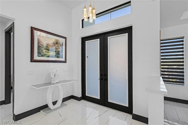 tiled entryway with a notable chandelier and french doors