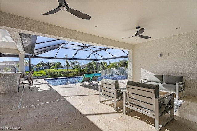 view of patio / terrace with outdoor lounge area, an outdoor wet bar, ceiling fan, and a lanai