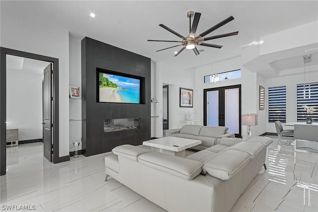 living room with a large fireplace, french doors, and ceiling fan