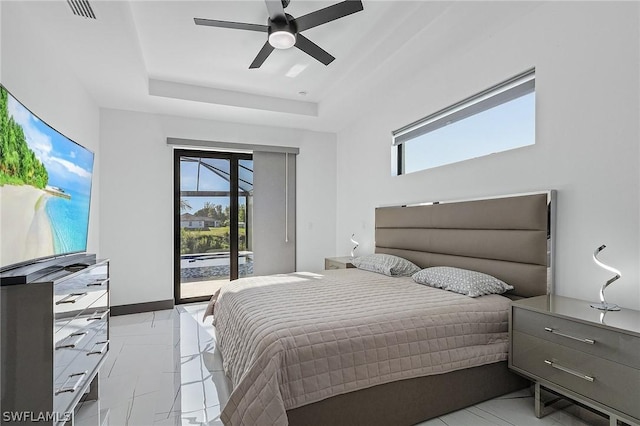 bedroom featuring multiple windows, access to outside, a raised ceiling, and ceiling fan