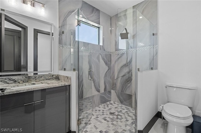 bathroom with a shower with door, vanity, and toilet