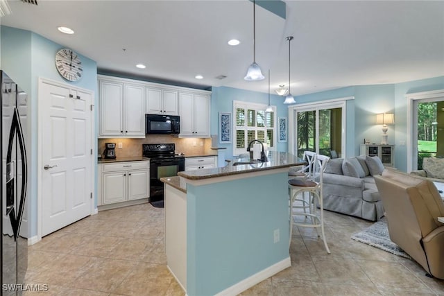 kitchen with a kitchen breakfast bar, sink, black appliances, pendant lighting, and white cabinets