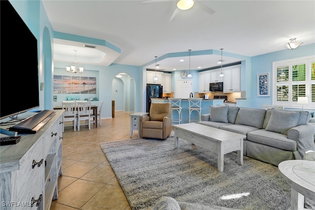 tiled living room with ceiling fan with notable chandelier