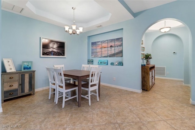 tiled dining space featuring a raised ceiling and a notable chandelier