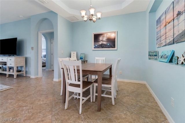 dining space with a tray ceiling and an inviting chandelier