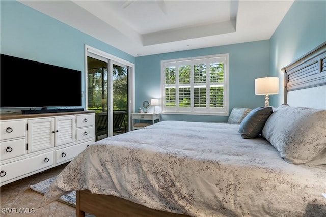 bedroom featuring access to exterior, ceiling fan, and a raised ceiling