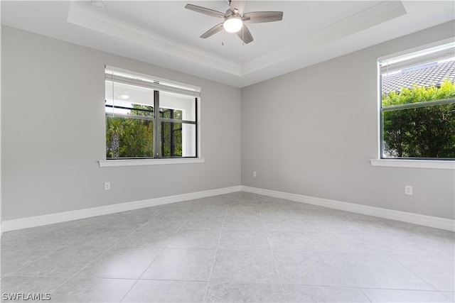 tiled spare room with a raised ceiling, ceiling fan, crown molding, and plenty of natural light