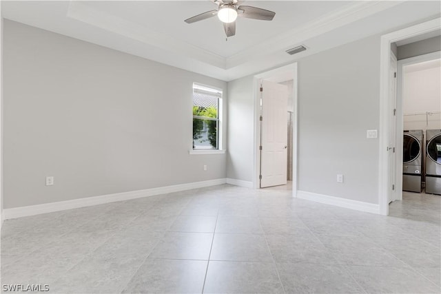 tiled empty room featuring a raised ceiling, ceiling fan, separate washer and dryer, and crown molding