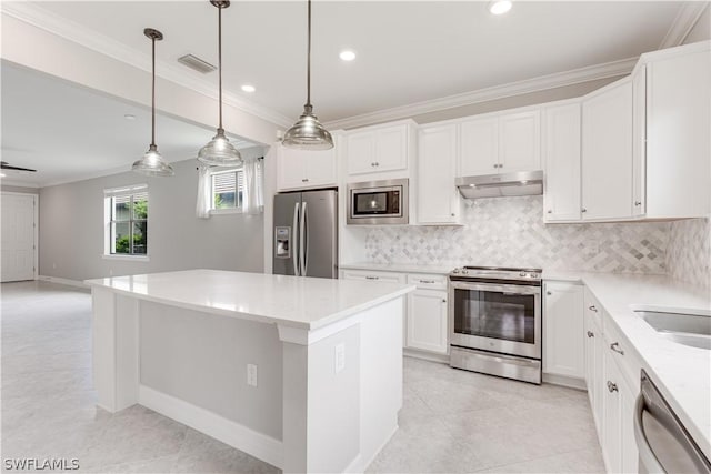 kitchen featuring a center island, hanging light fixtures, backsplash, white cabinets, and appliances with stainless steel finishes