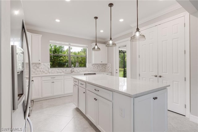 kitchen featuring a center island, light stone countertops, stainless steel fridge, white cabinetry, and decorative light fixtures