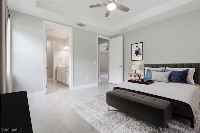 bedroom featuring ensuite bath, light tile patterned floors, ceiling fan, ornamental molding, and a tray ceiling