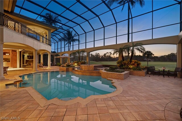 pool at dusk with a patio and glass enclosure