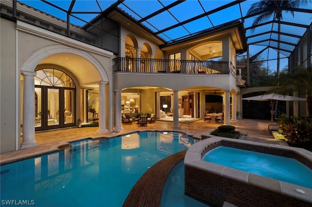 rear view of property with french doors, a balcony, glass enclosure, and a patio area