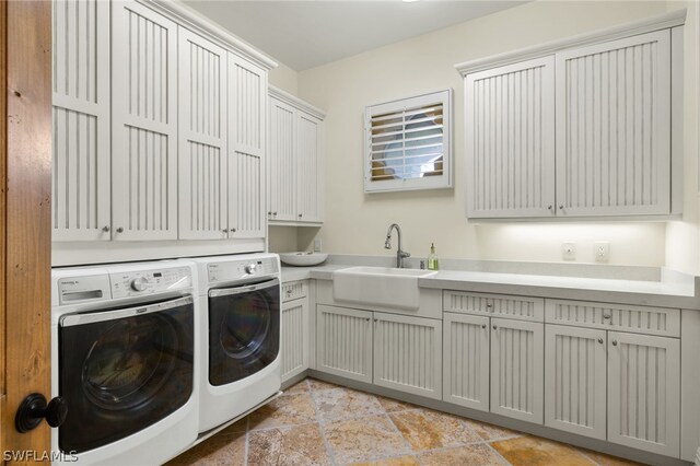 clothes washing area with cabinets, washing machine and dryer, and sink