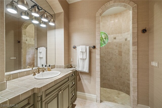 bathroom featuring tile patterned flooring, vanity, and a tile shower