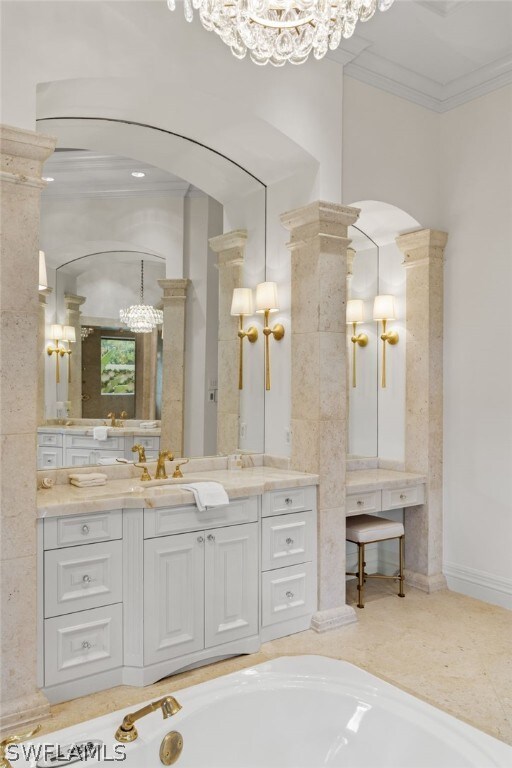 bathroom with vanity, a tub to relax in, ornamental molding, and decorative columns