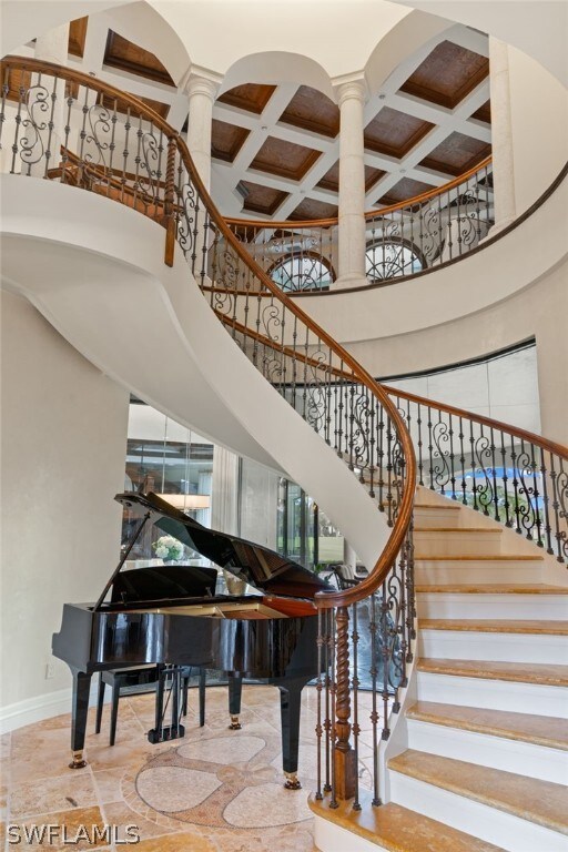 stairway with a towering ceiling and coffered ceiling