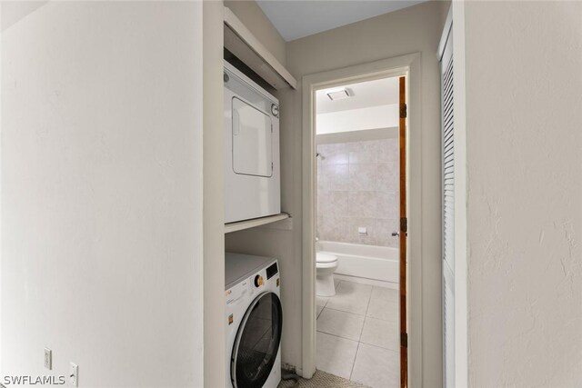 clothes washing area with stacked washer / dryer and light tile patterned floors