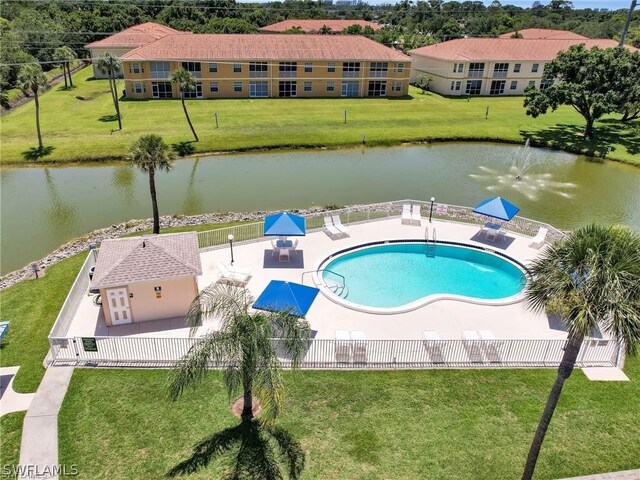 view of swimming pool with a patio, a water view, and a lawn